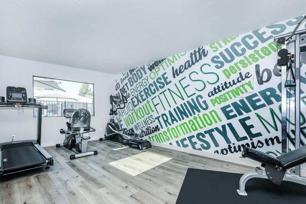 A gym with a wall covered in fitness related words.