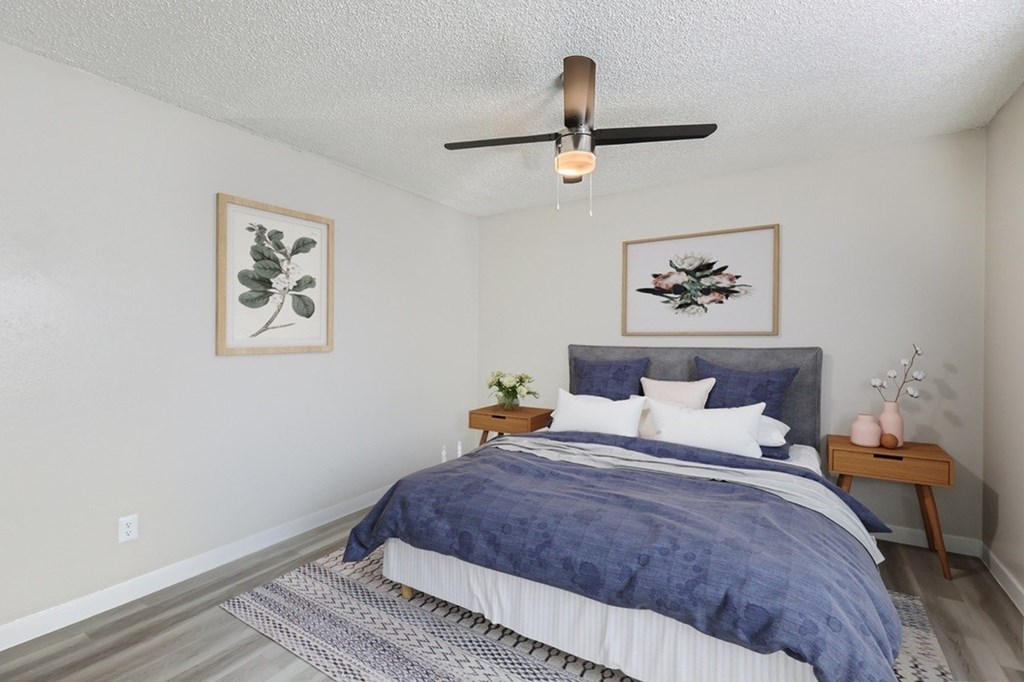A bedroom with a bed, nightstand, and two framed pictures on the wall.