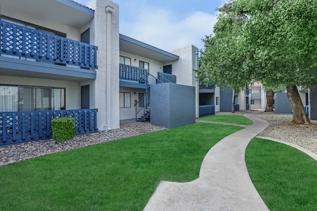 A pathway leads through a grassy area in front of apartment buildings.