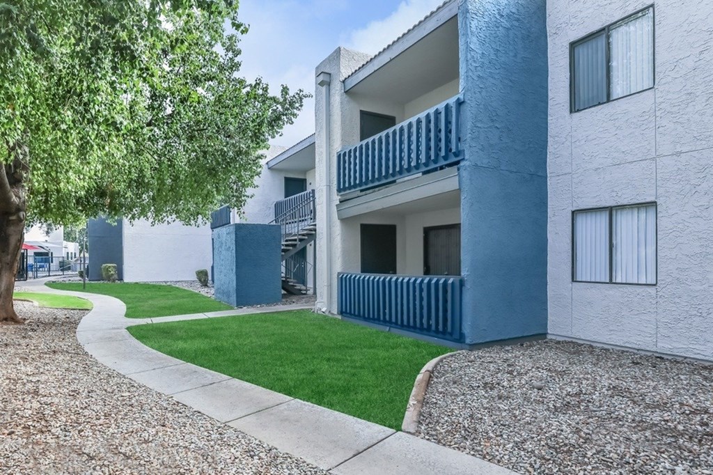 A blue and white apartment building with a tree in front.