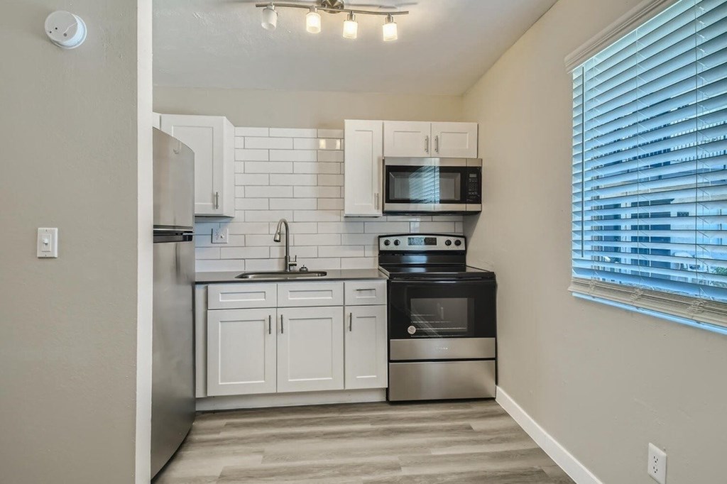A kitchen with white cabinets and a black oven.