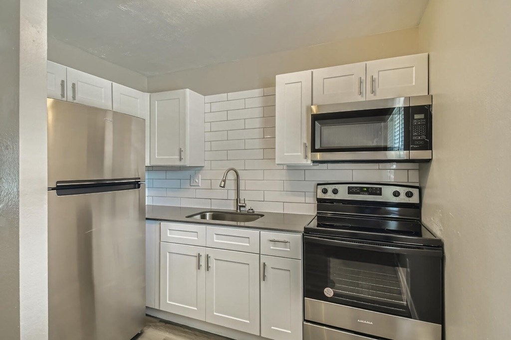 A kitchen with white cabinets and black appliances.