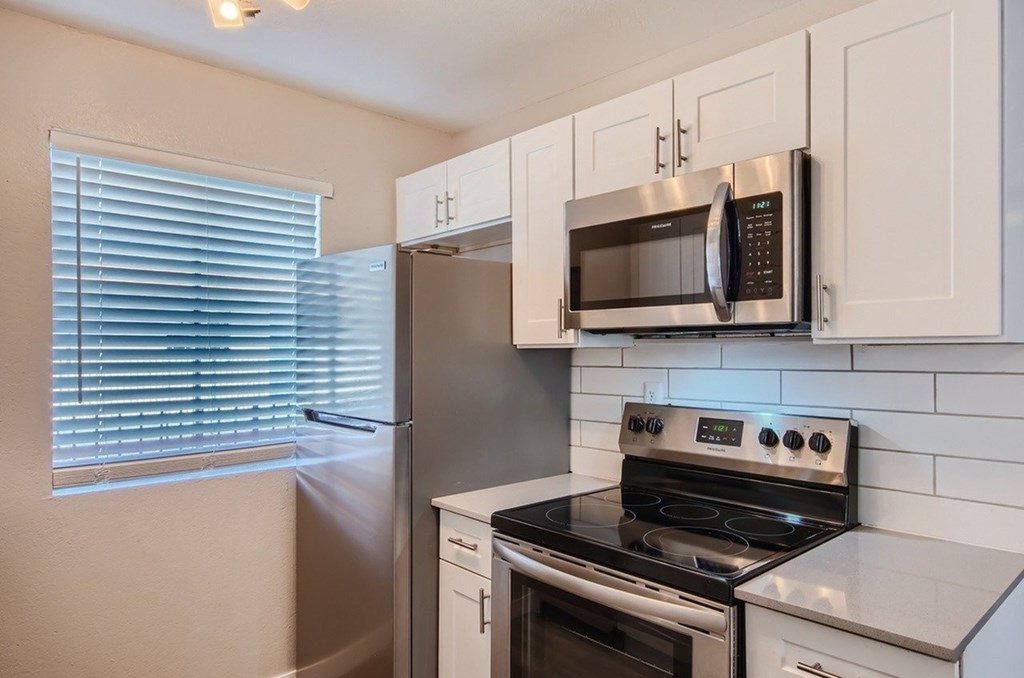 A kitchen with a stove, microwave, and refrigerator.