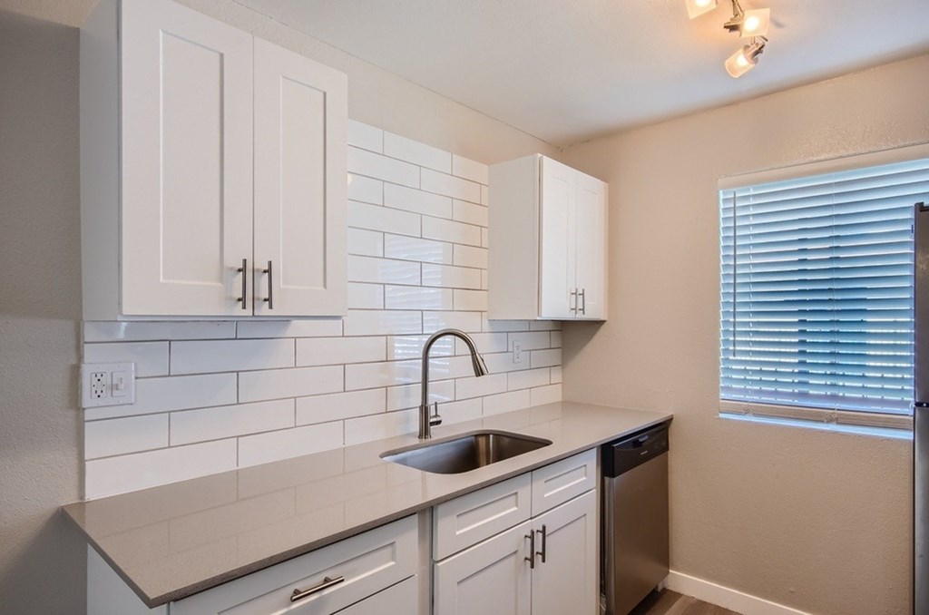 A kitchen with white cabinets and a white tiled backsplash.