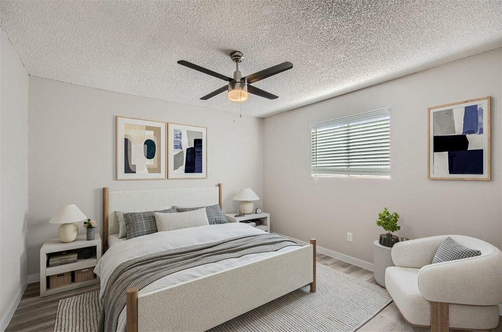 A bedroom with a bed, chair, and ceiling fan.