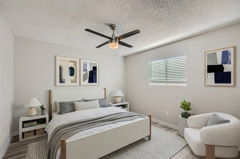 A bedroom with a bed, chair, and ceiling fan.