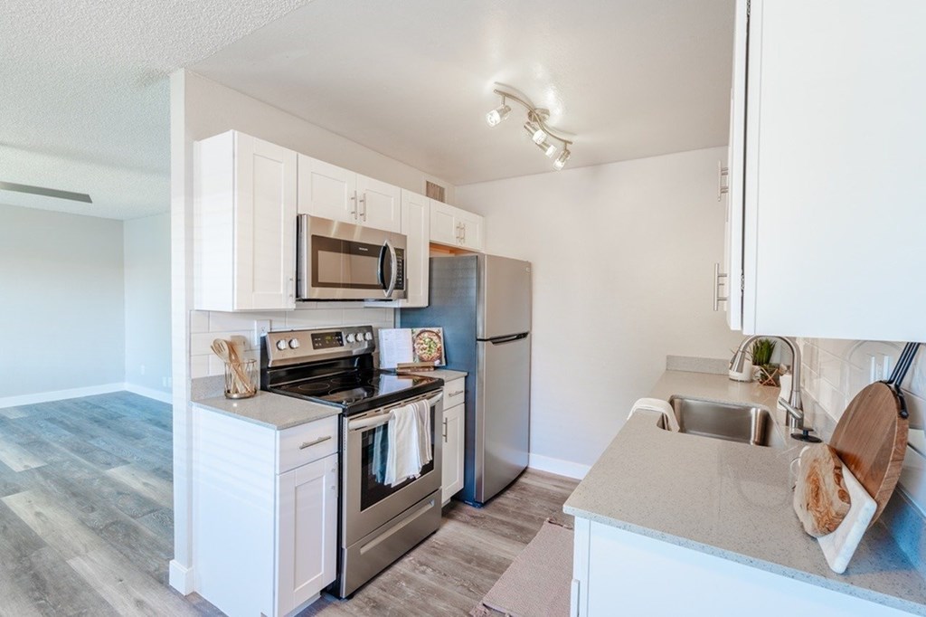 A kitchen with white cabinets and a stainless steel refrigerator.