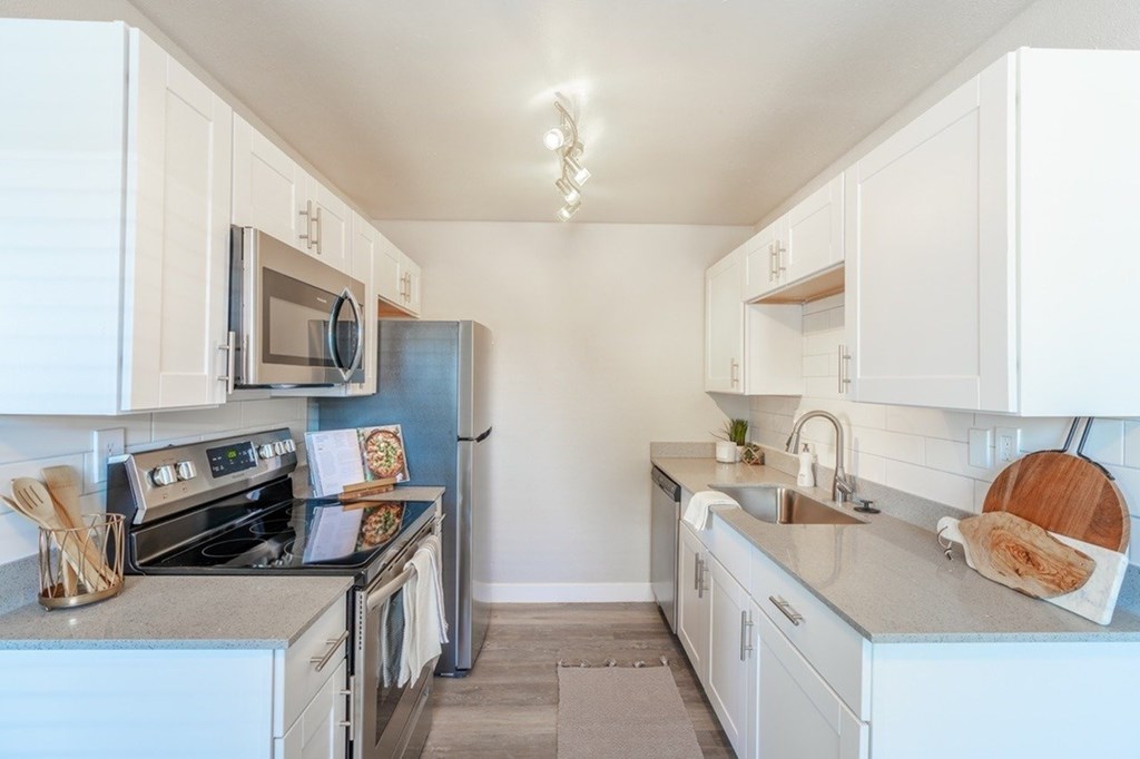 A kitchen with white cabinets and a grey counter top.