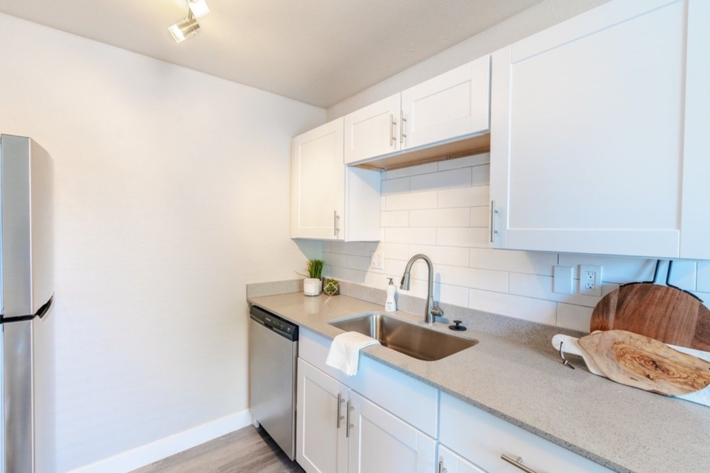 A kitchen with white cabinets and a stainless steel refrigerator.