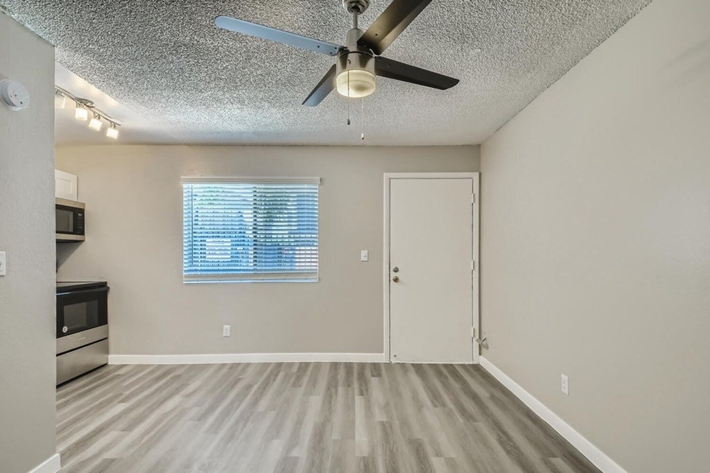A room with a ceiling fan and a window with blinds.