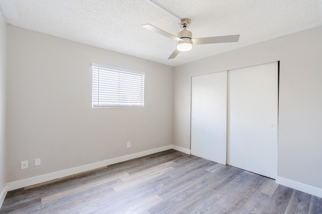 A room with a ceiling fan and a window with blinds.