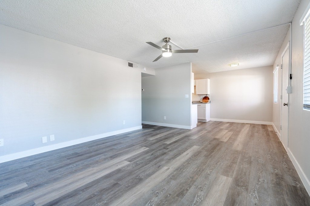 A room with a ceiling fan and wooden flooring.