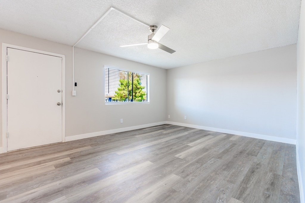 A room with a white ceiling, a window with blinds, and a wooden floor.