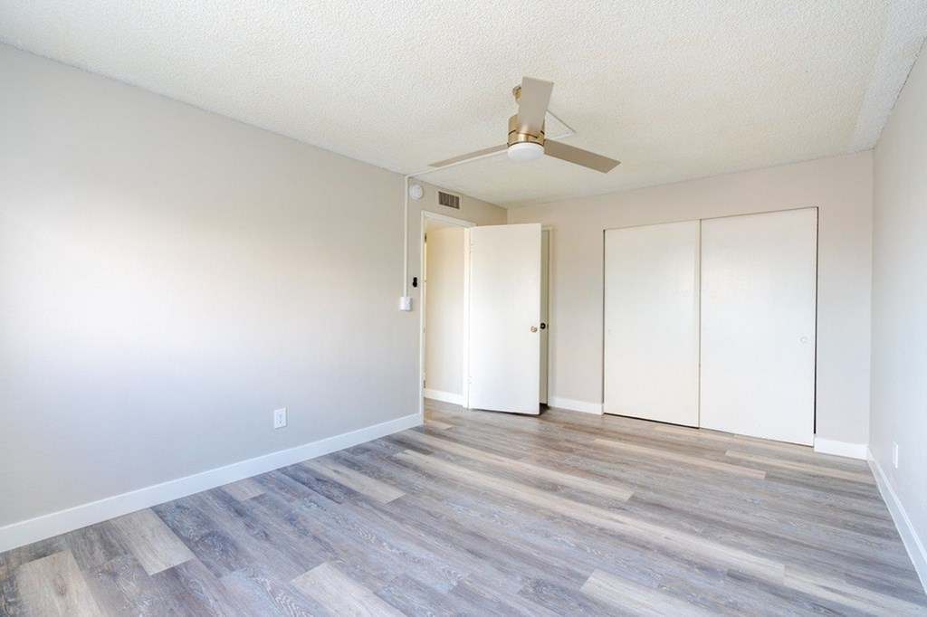 A room with a ceiling fan and wood flooring.