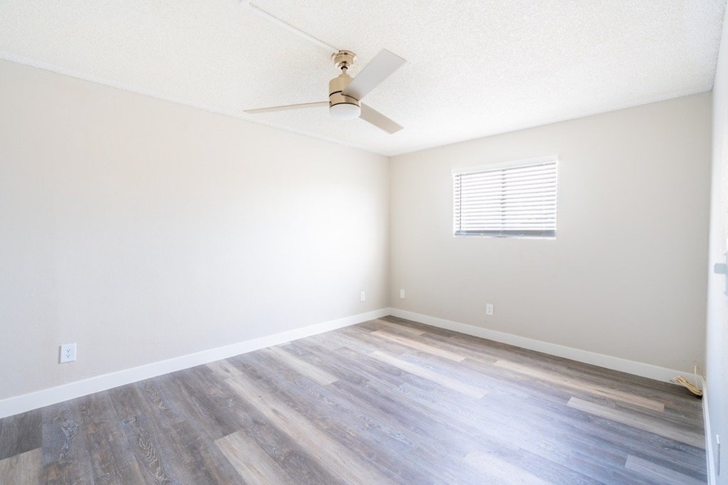 A room with a ceiling fan and a window with blinds.