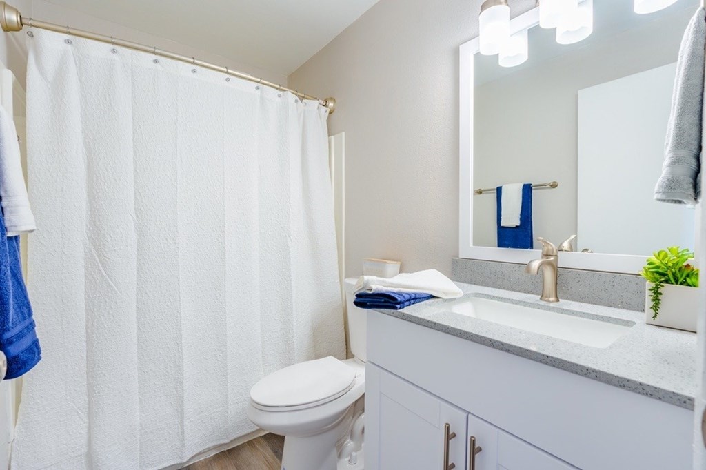 A white bathroom with a toilet, sink, and shower curtain.