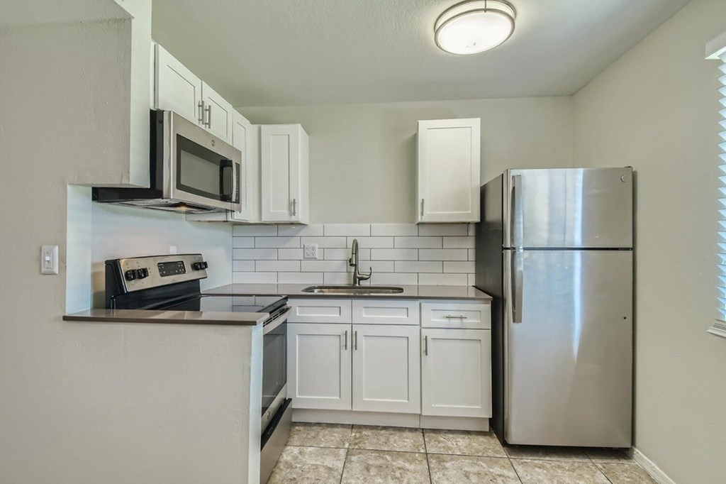 A kitchen with white cabinets and a stainless steel refrigerator.