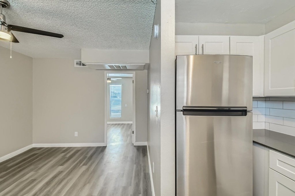 A kitchen with a stainless steel refrigerator and wooden flooring.