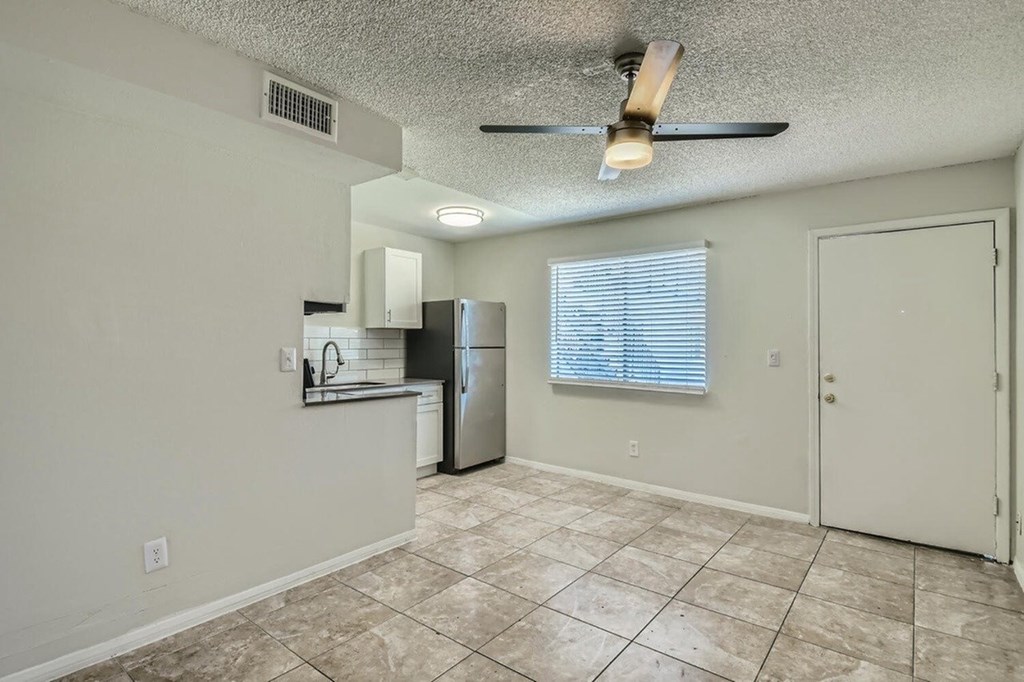 A kitchen with a refrigerator, sink, and a fan.