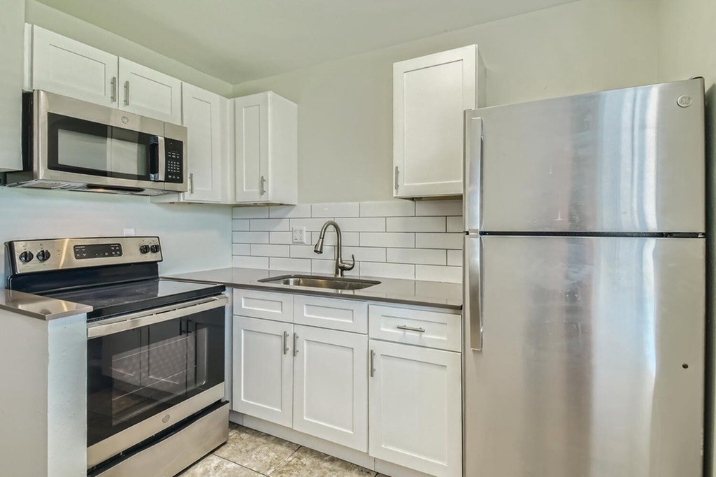 A kitchen with a stainless steel refrigerator, oven, and microwave.
