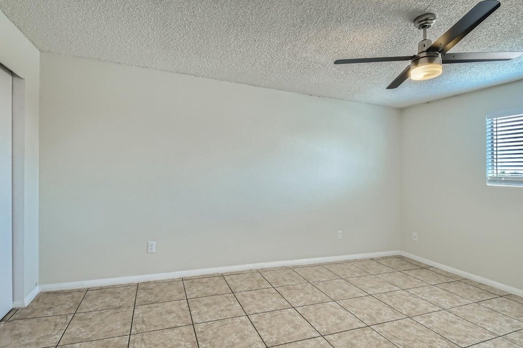 A room with a ceiling fan and tiled floor.