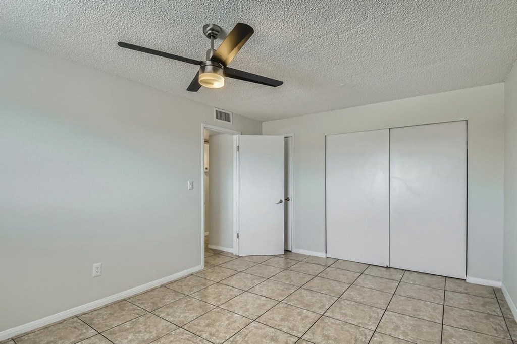 A room with a ceiling fan and tiled flooring.