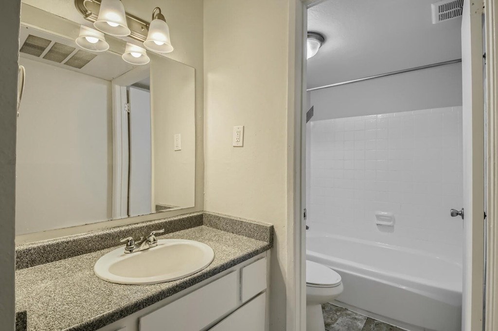 A bathroom with a sink, mirror, and bathtub.