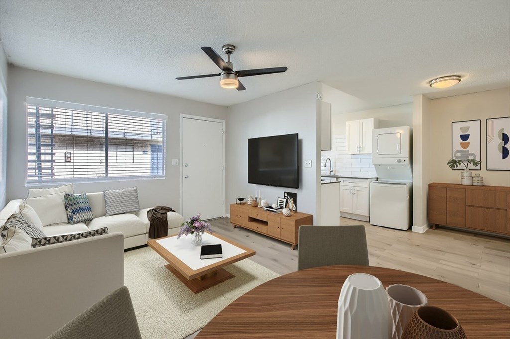 A living room with a white couch, a wooden coffee table, and a flat screen TV.