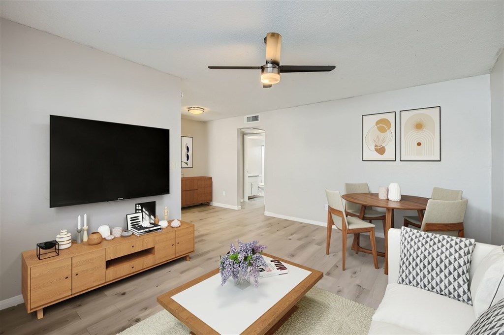 A living room with a flat screen TV, a coffee table, and a dining table.
