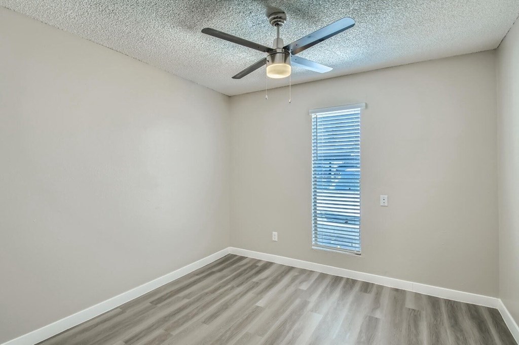 A room with a ceiling fan and a window with blinds.