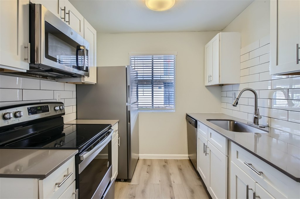 A kitchen with white cabinets and black appliances.