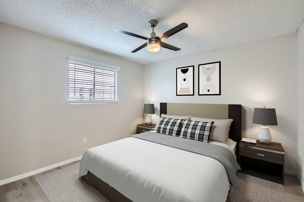 A bedroom with a bed, two nightstands, and a ceiling fan.