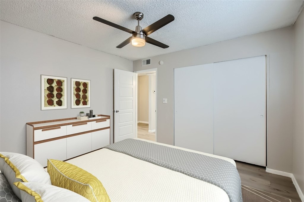 A bedroom with a bed, dresser, and a ceiling fan.
