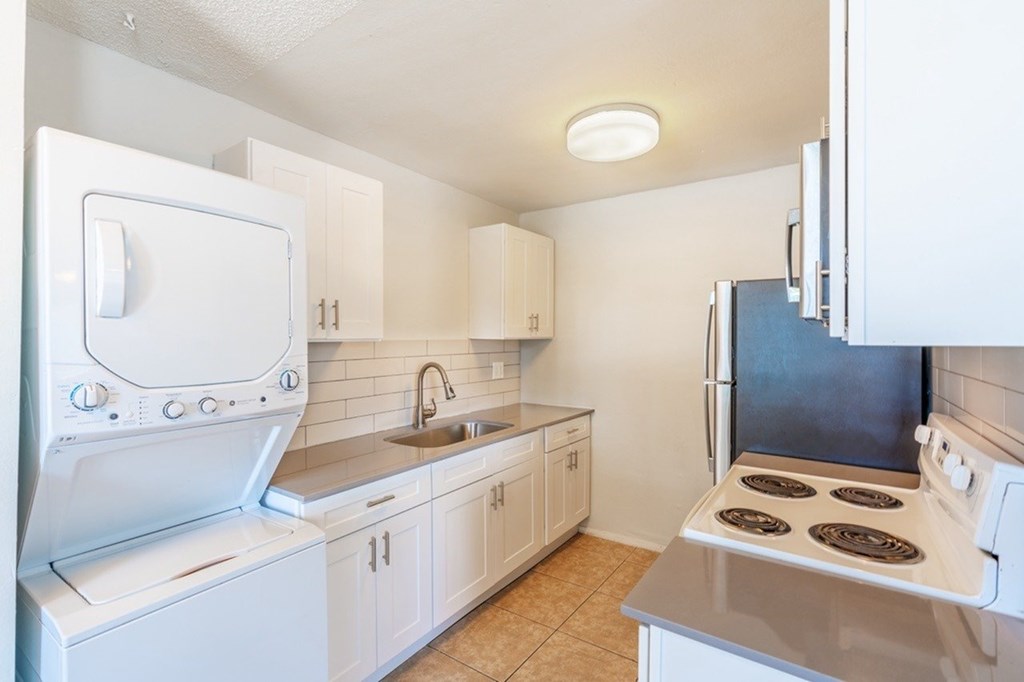 A white kitchen with a stove, sink, and oven.