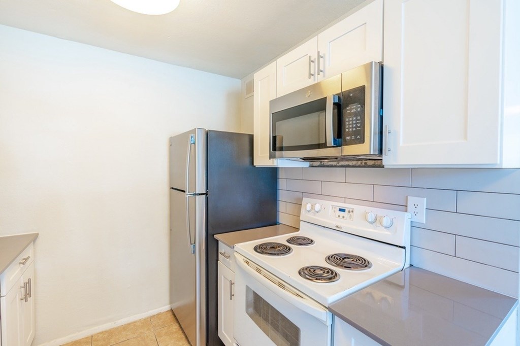 A kitchen with a stove, microwave, and refrigerator.