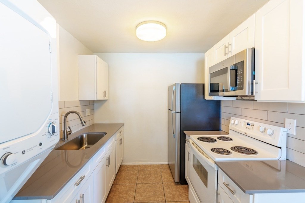 A kitchen with white cabinets and black appliances.