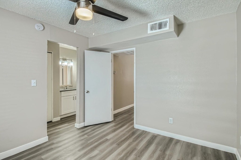 A room with a ceiling fan and a door leading to another room.