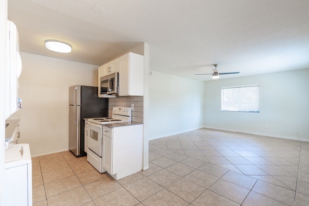 A kitchen with white appliances and a tiled floor.