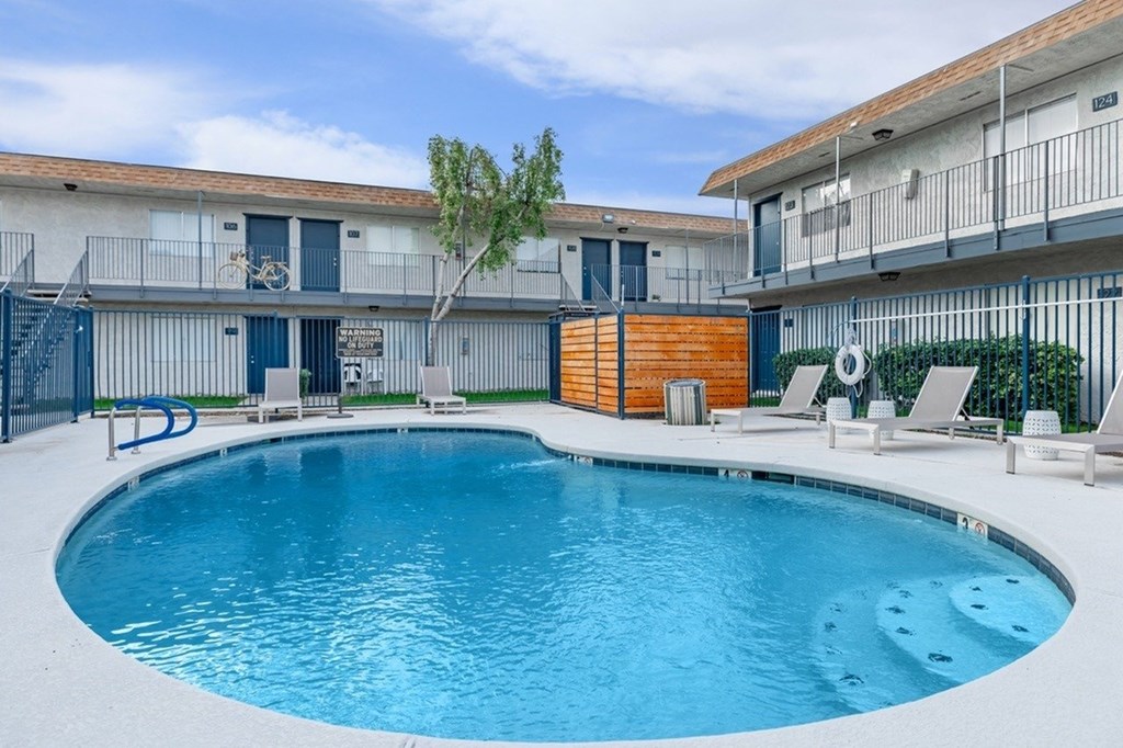 A swimming pool in front of a building with a tree.