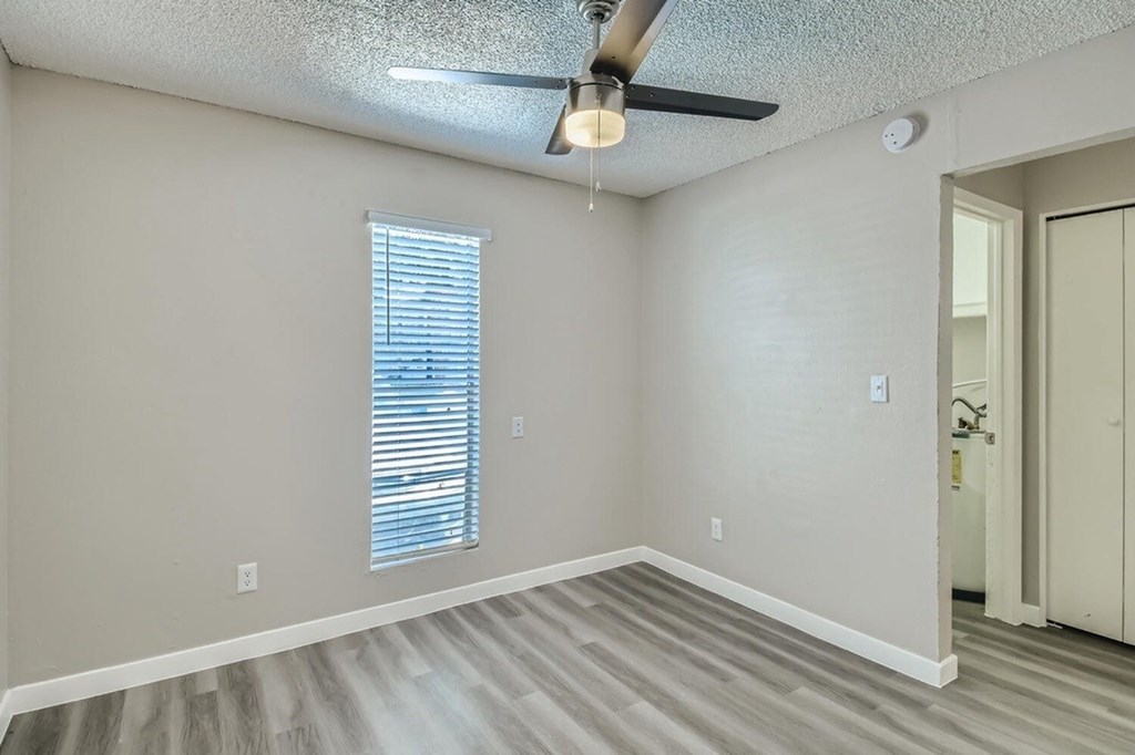 A room with a ceiling fan and a window with blinds.