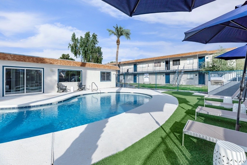 A pool with a white fence and a blue umbrella.