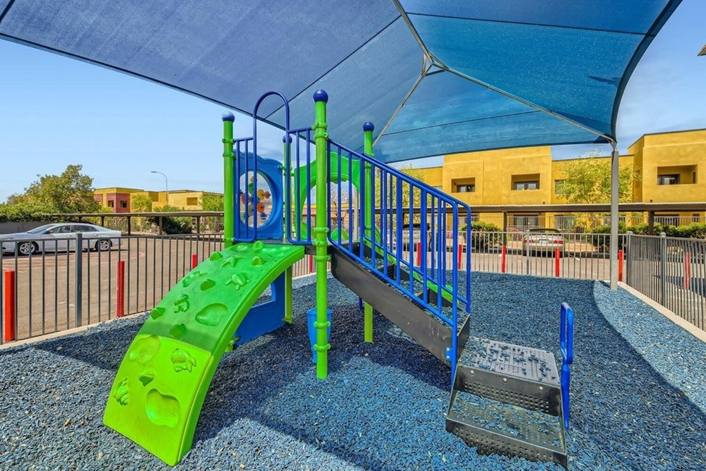 A playground with a green slide and blue and green play equipment.