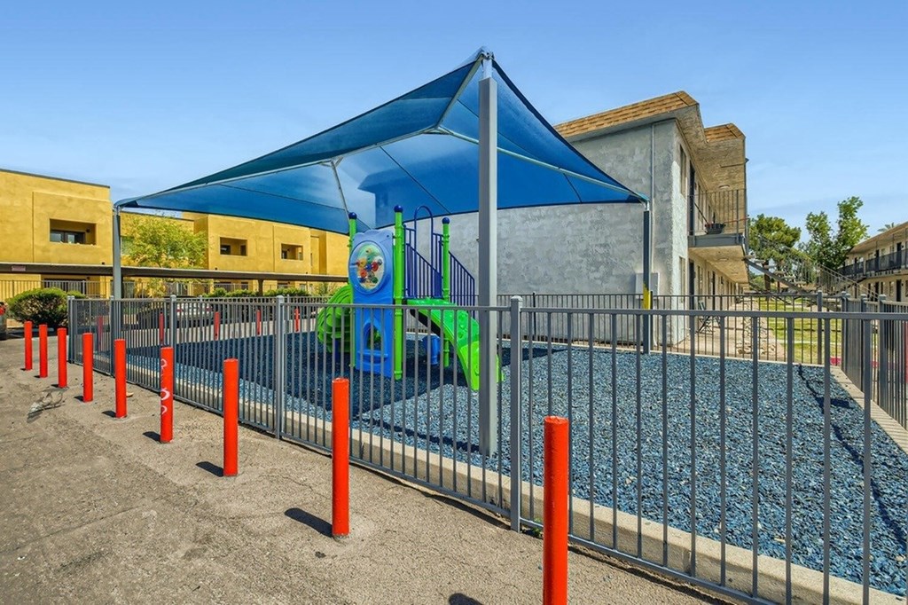 A playground with a blue canopy and orange posts.
