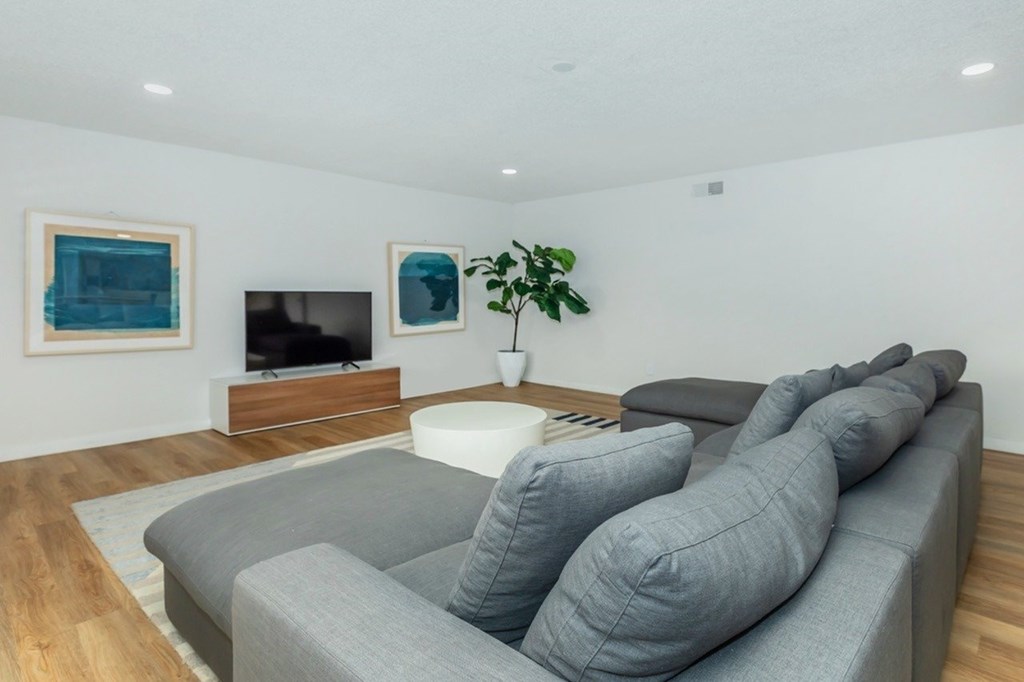 A grey couch with a white coffee table in front of a television.
