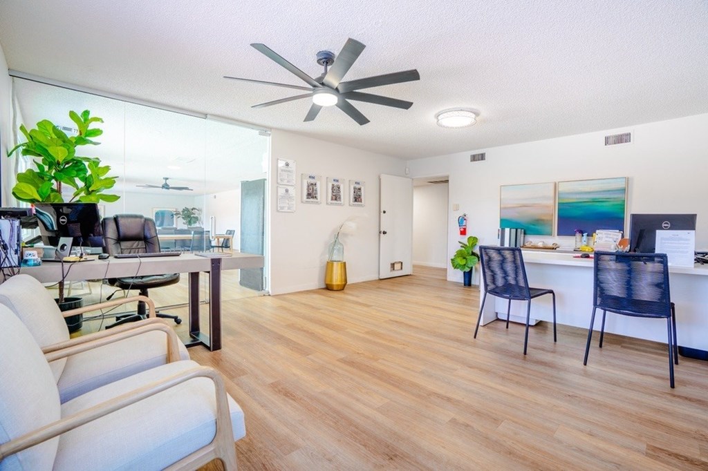 A living room with a ceiling fan and a dining table with chairs.