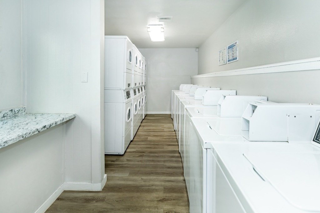A laundry room with a row of washers and dryers.