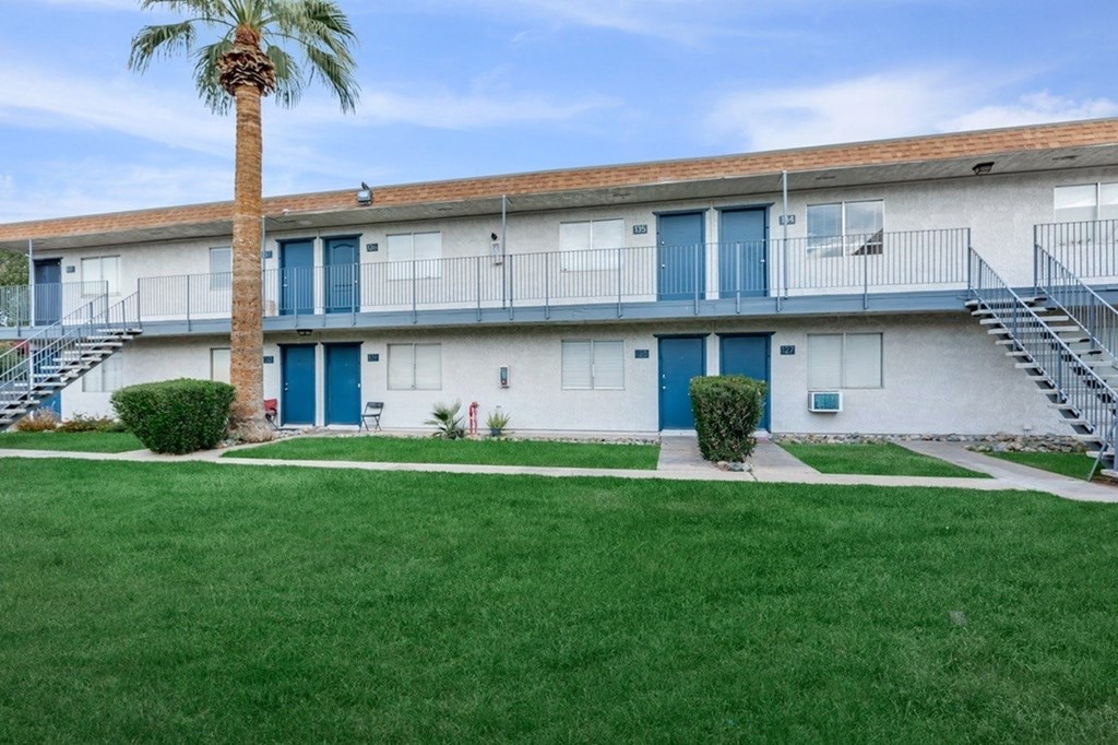 A building with blue doors and windows is surrounded by a green lawn.