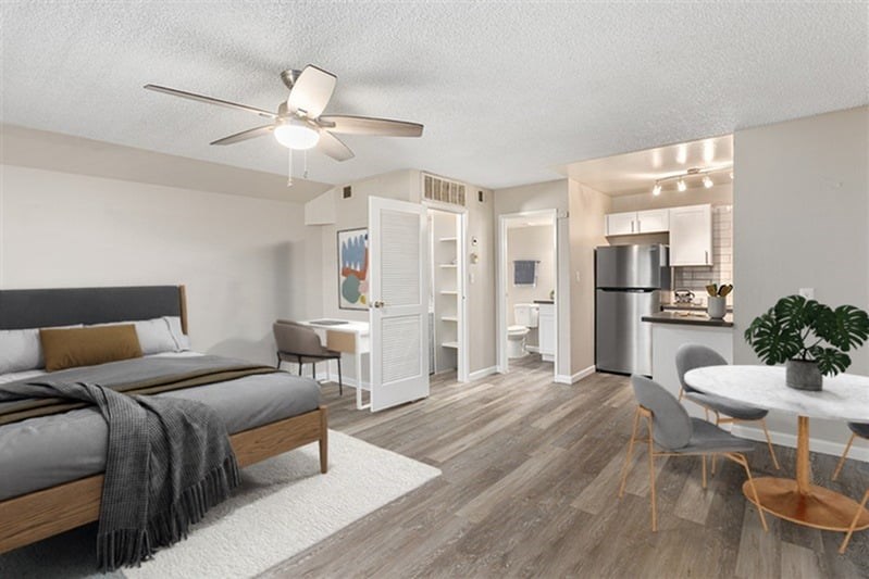 A bedroom with a bed, chair, and a ceiling fan.