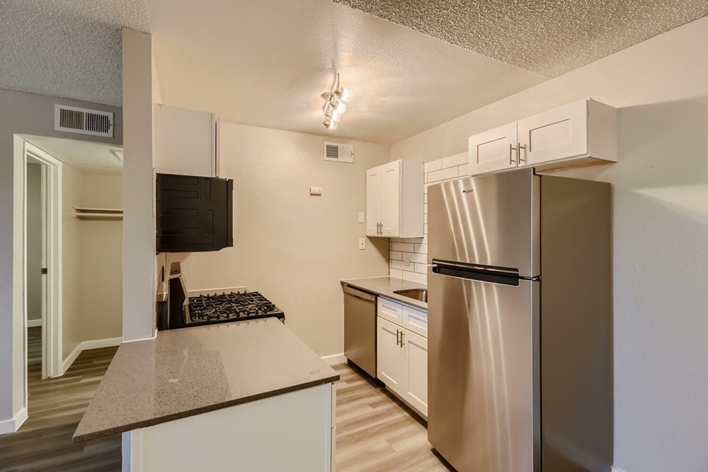 A kitchen with a refrigerator, microwave, and oven.
