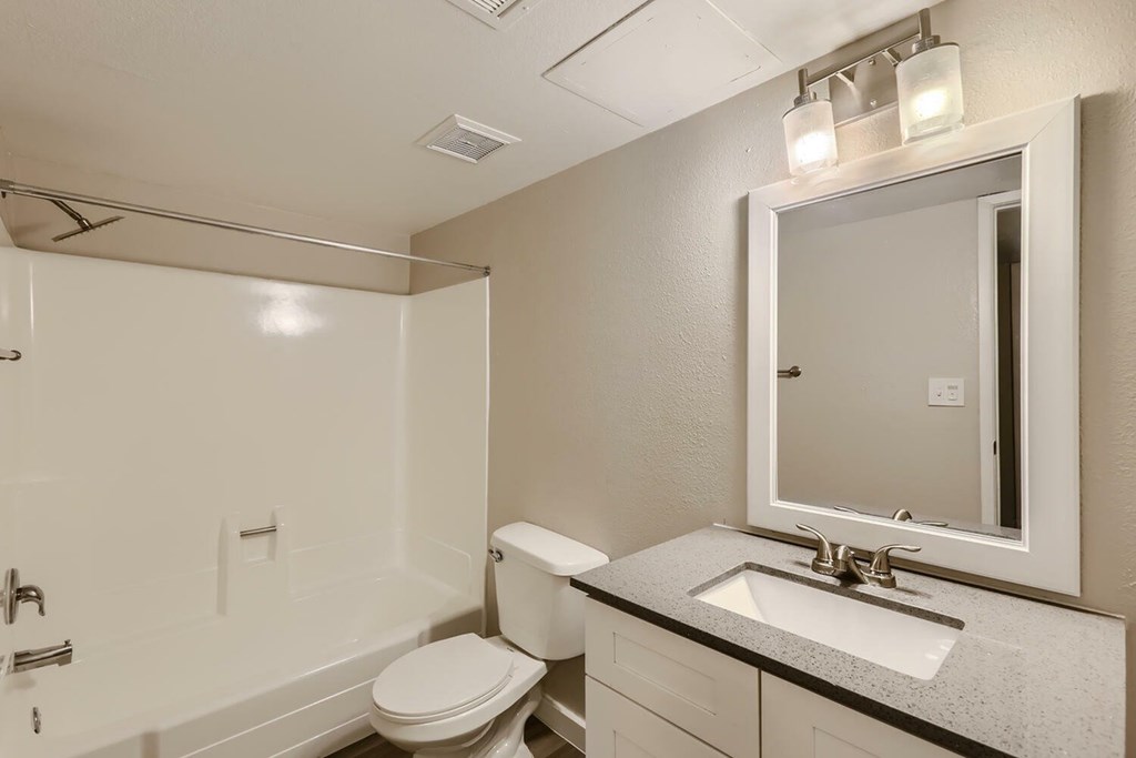 A white bathroom with a toilet, sink, and mirror.